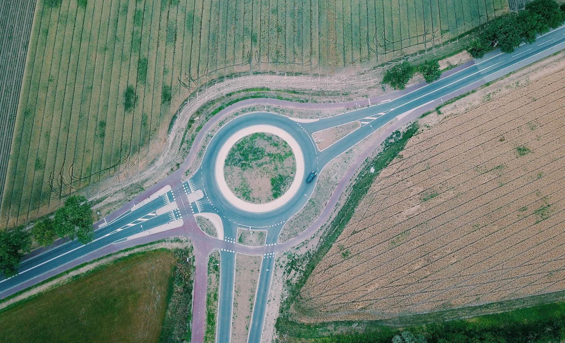 Luchtfoto van een rotonde met rode fietspaden tussen weilanden
