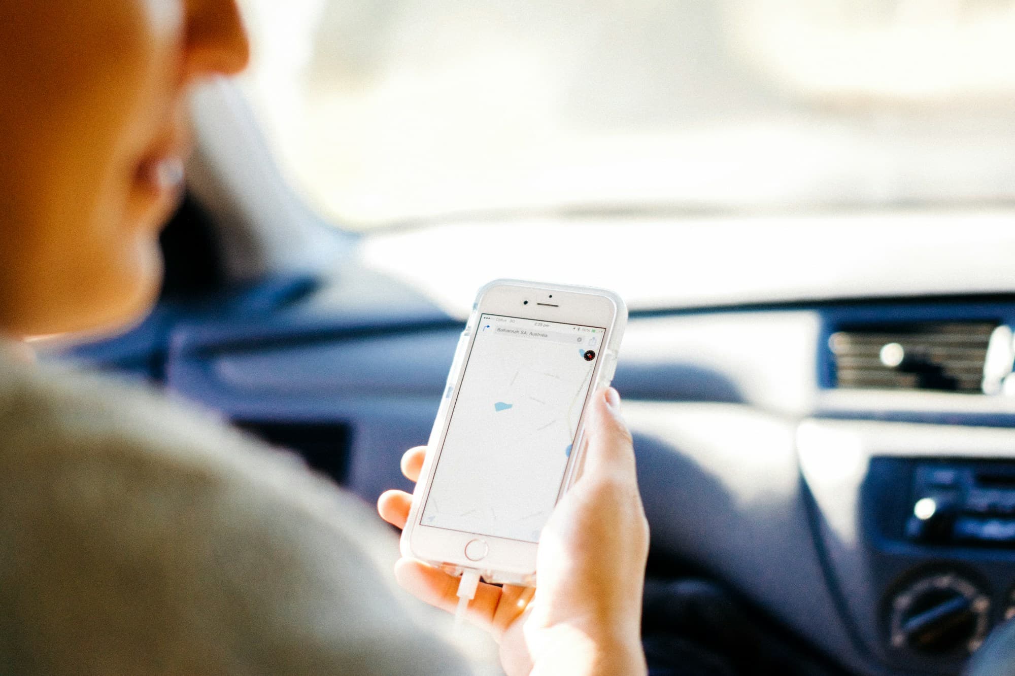 Iemand bekijkt een kaart op een telefoon in de auto